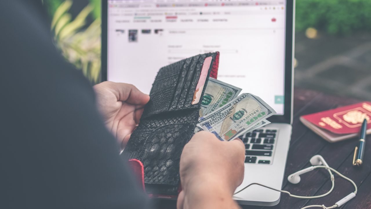 パソコンを見ながら財布から紙幣を取り出す女性